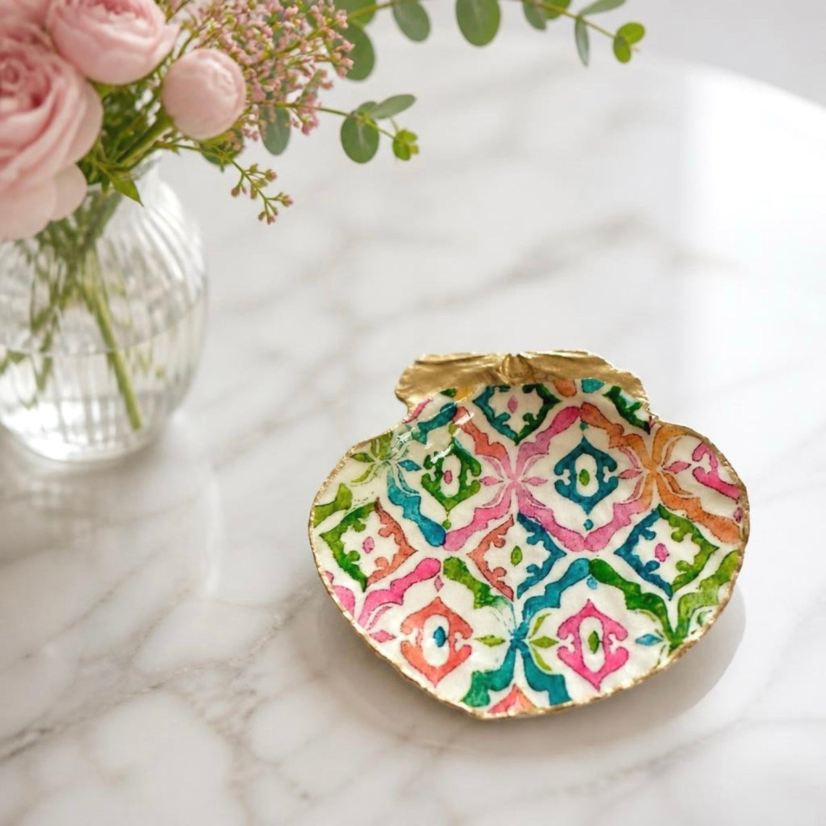 A decorative neon chinoiserie dish with a colorful geometric pattern and gold rim